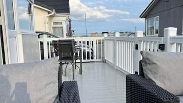 A covered outdoor deck with wicker furniture and a view of the sea.