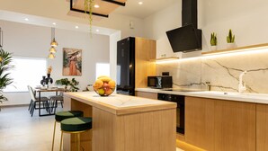 A modern kitchen with a wooden island, black appliances, and a marble backsplash. - Casa Dionysia (Platanias)