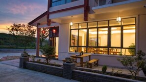 A building with a covered outdoor seating area, a brick planter, and a red stop sign. - Hengyou Hostel (Wuyishan)