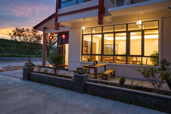 A building with a covered outdoor seating area, a brick planter, and a red stop sign. - Hengyou Hostel (Wuyishan)
