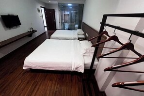 A hotel room with two beds, a TV, a coat rack, and a bathroom visible through a glass door. - Hengyou Hostel (Wuyishan)