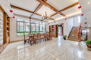 A spacious room with a dining area, a staircase, and large windows. - Hengyou Hostel (Wuyishan)