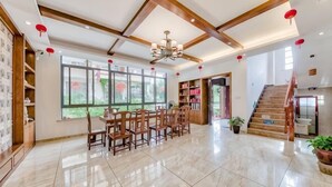 A spacious room with a dining area, large windows, a staircase, and a chandelier. - Hengyou Hostel (Wuyishan)