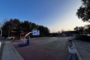 An outdoor basketball court with a digital scoreboard and a traditional pavilion in the background. - Hengyou Hostel (Wuyishan)