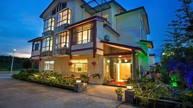 A multi-story house with a balcony, large windows, and outdoor seating area with plants. - Hengyou Hostel (Wuyishan)