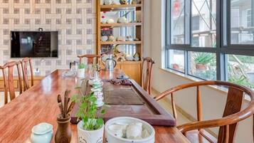 Un comedor con una mesa de madera, sillas y un televisor montado en la pared.