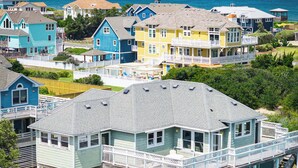 Un edificio frente al mar con varios pisos, balcones, piscina y vista al océano.