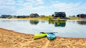 Une vue sur le lac, avec des maisons, des kayaks et une plage de sable.