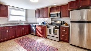 A modern kitchen with dark wooden cabinets, stainless steel appliances, and a patterned rug on the floor.