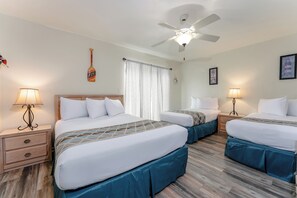 A hotel room with two beds, a ceiling fan, and a nightstand with a lamp.