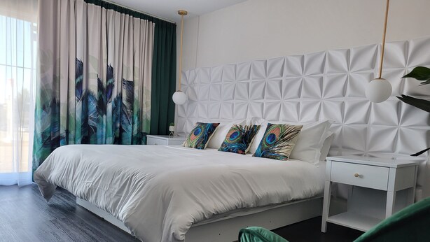 Ein modernes Schlafzimmer mit einem großen Bett, einem weißen Kopfteil und dekorativen Kissen.