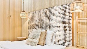 A bed with a headboard covered in circular patterns, a wooden wardrobe, and two hanging lamps. - Charmant appartement Paris 12e (Paris)