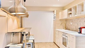 A modern kitchen with a dining area, built-in cabinets, and pendant lighting. - Charmant appartement Paris 12e (Paris)
