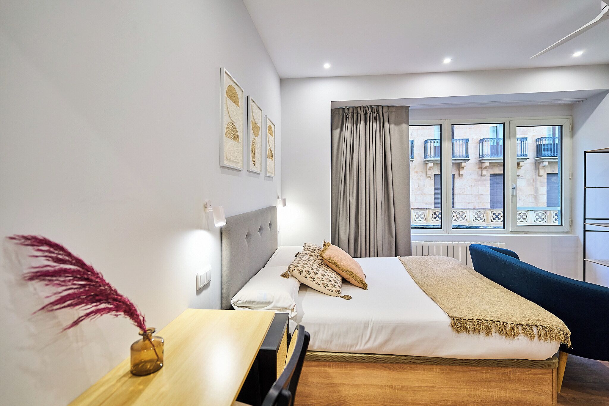 Una habitación de hotel moderna con cama, mesita de noche y vistas al balcón exterior.