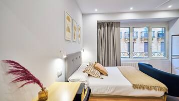Una habitación de hotel moderna con cama, mesita de noche y vistas al balcón exterior.