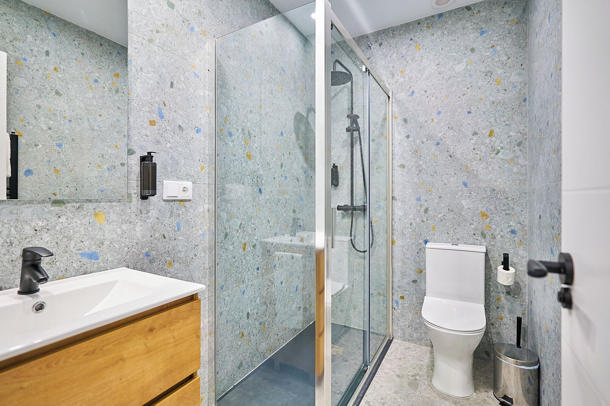 A modern bathroom with a freestanding sink, a glass-enclosed shower, and a toilet.
