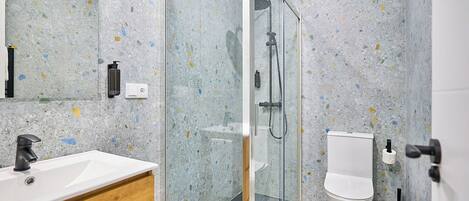 A modern bathroom with a freestanding sink, a glass-enclosed shower, and a toilet.