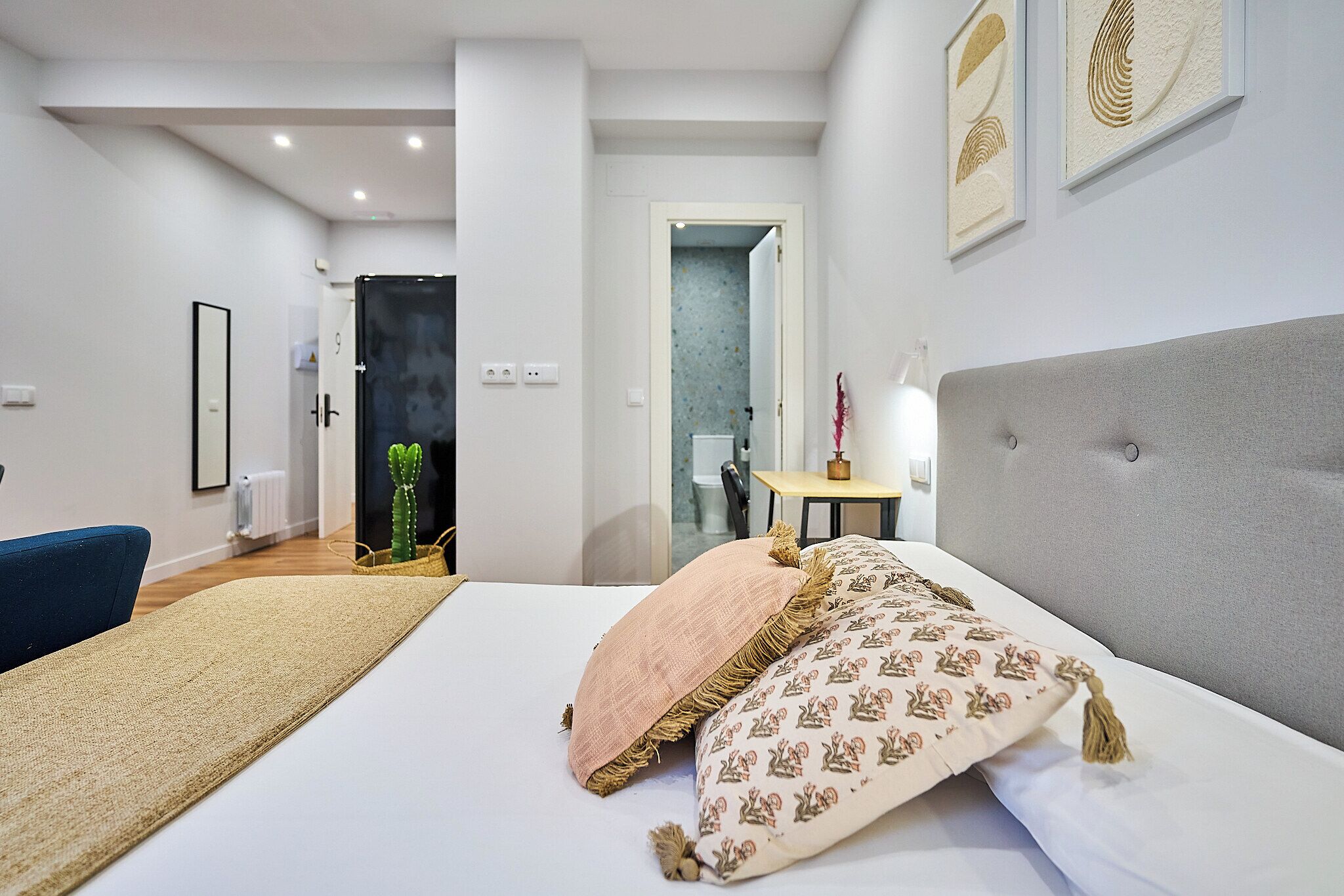 Une chambre d’hôtel moderne avec un grand lit, une chaise bleue et une petite table avec une lampe.