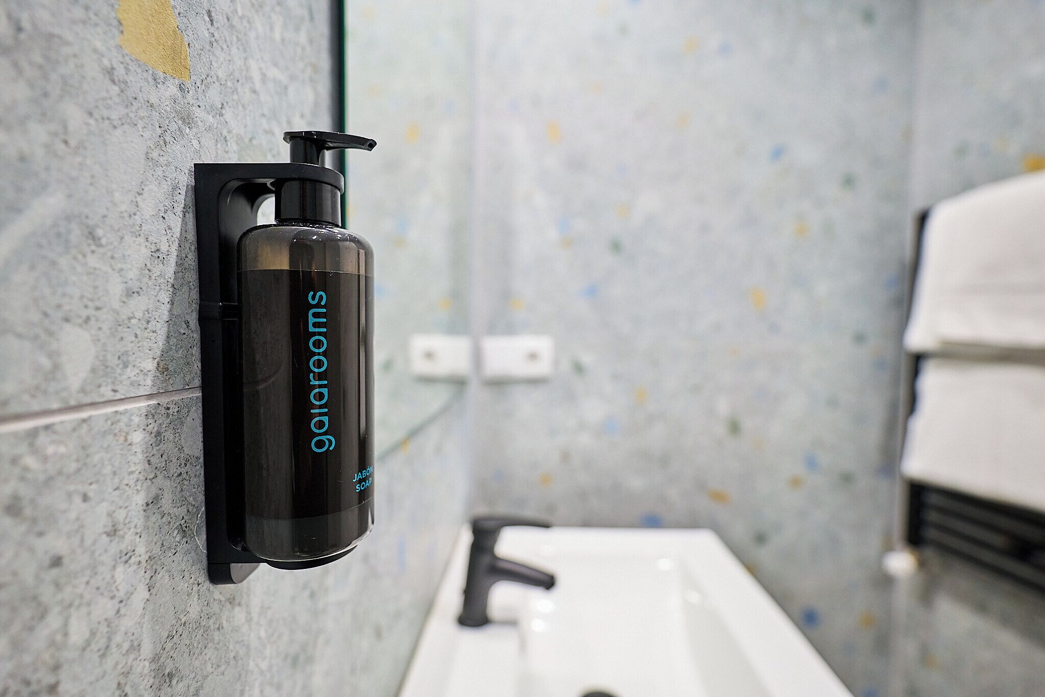 A bathroom with a wall-mounted soap dispenser and a sink.