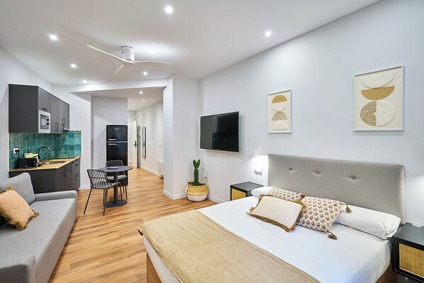 Una habitación de hotel moderna con cama, sofá, zona de comedor y cocina.