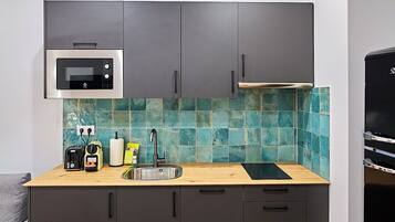 A modern kitchen with grey cabinets, a microwave, a sink, and a wooden countertop.