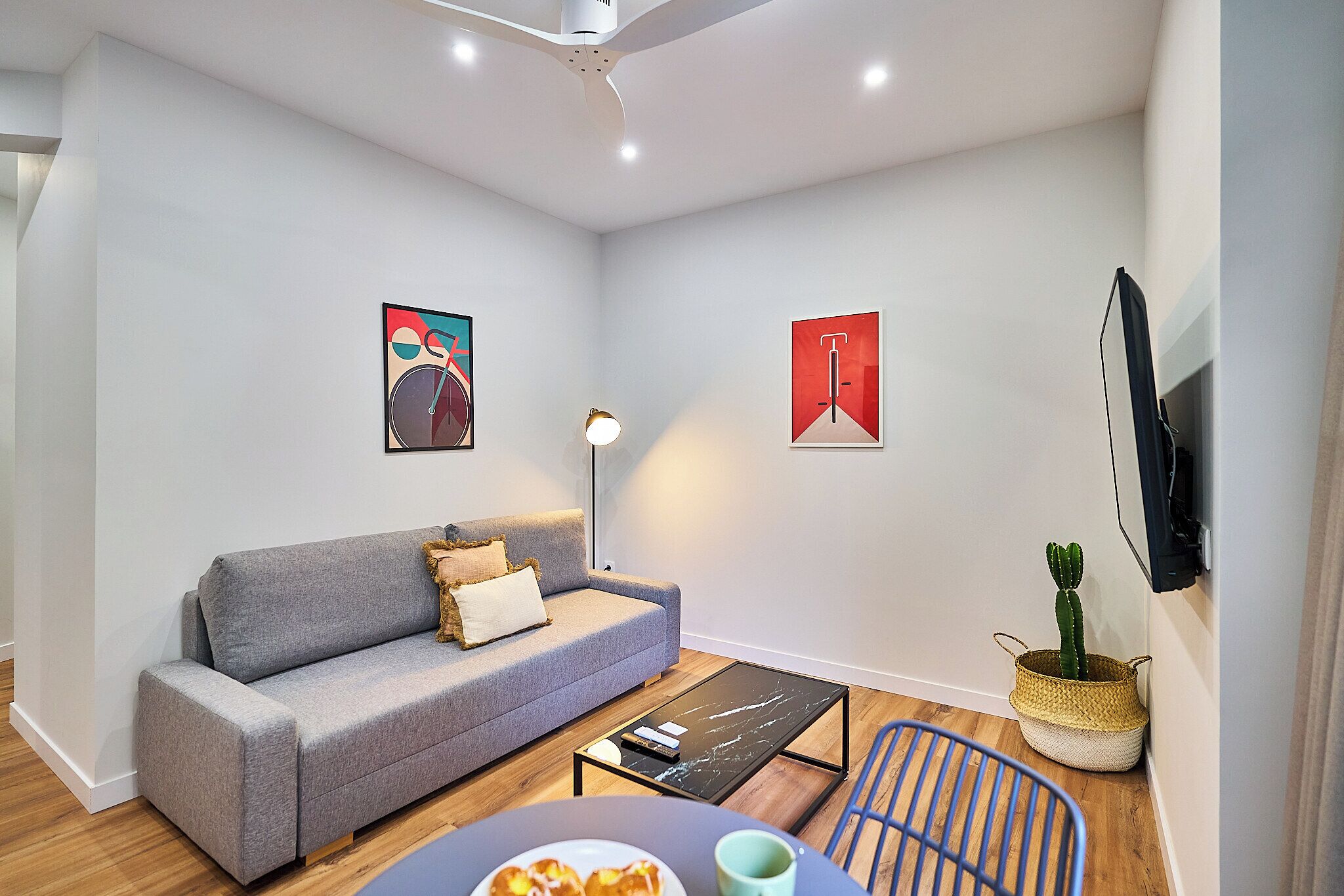 A modern living room with a grey sofa, a coffee table, a lamp, and a cactus plant.