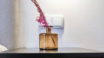 Een nachtkastje met een vaas met gedroogde bloemen en een lamp.