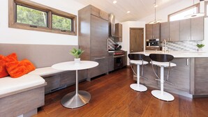 A modern kitchen with wooden cabinets, a built-in oven, and a bar area with stools. - Ocean View Craftsman Home - Great Location + Walk to Beach (Encinitas)