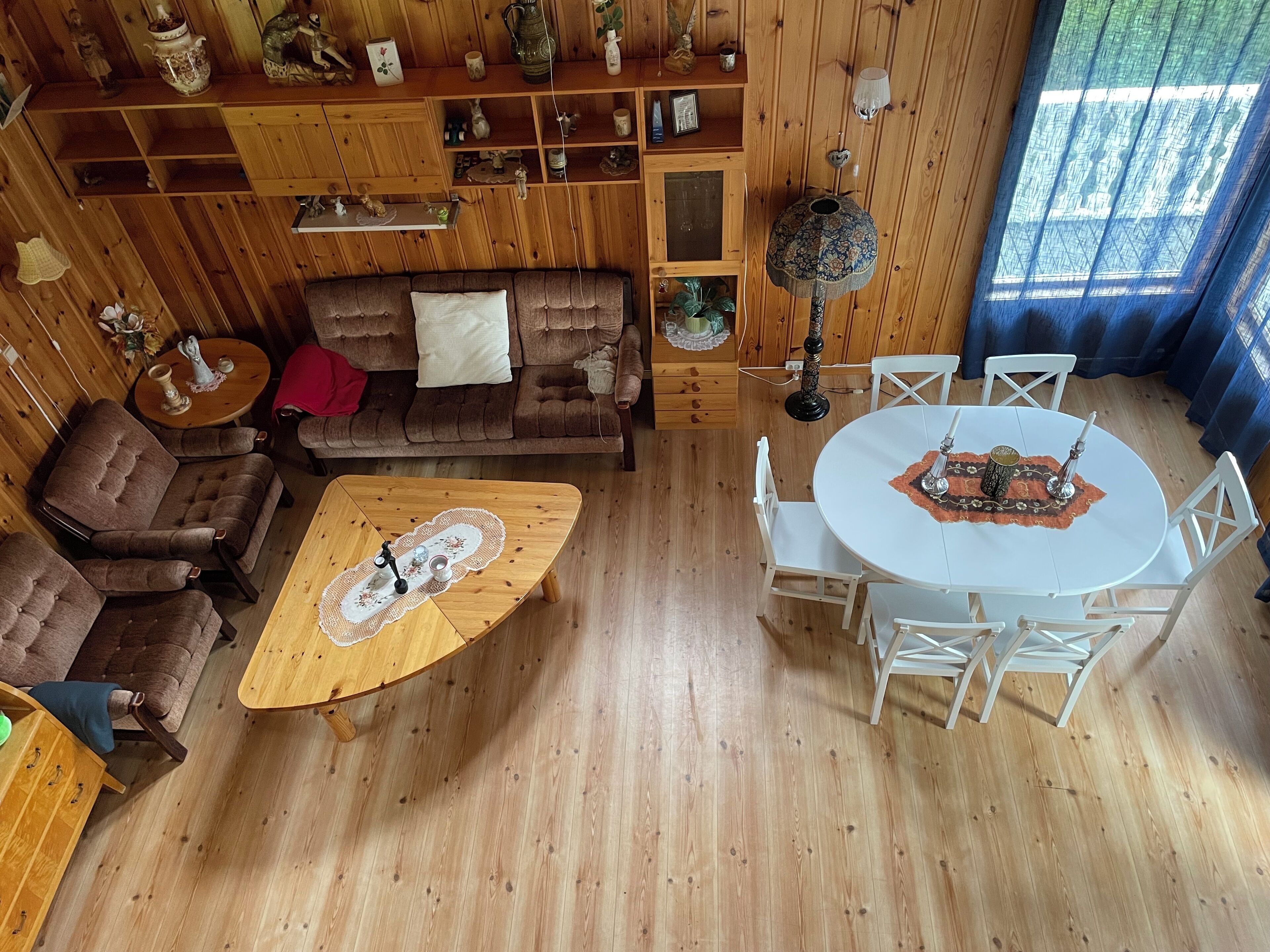 A cozy room with a wooden floor, a brown sofa, a round coffee table, and a white dining table with chairs.