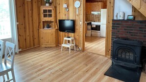 A wooden interior with a TV, a fireplace, and a kitchen area.