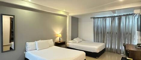 Ein modernes Hotelzimmer mit zwei Betten, einem Schreibtisch und einem Spiegel.