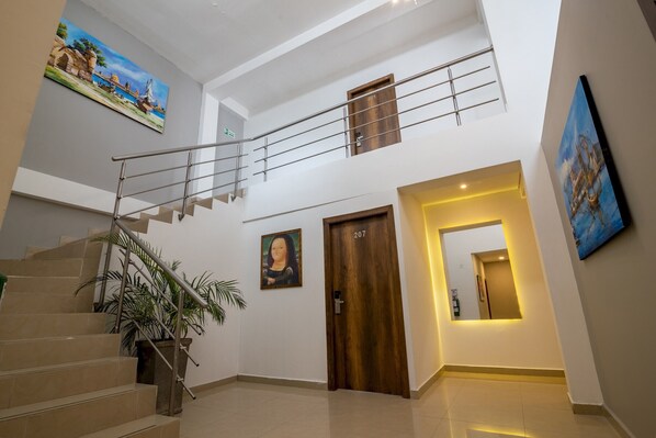 Un intérieur moderne avec un escalier, une porte en bois portant le numéro 207 et des œuvres d’art accrochées aux murs.
