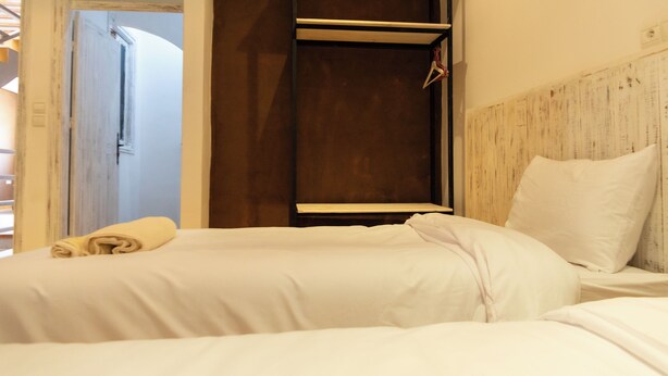 Habitación de hotel con dos camas, cabecera de madera y armario con perchero.