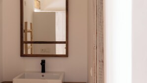 A bathroom with a white sink, a mirror, and wooden flooring. - Dakhla Roof Top (Dakhla)