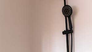 A black portable showerhead mounted on a wall. - Dakhla Roof Top (Dakhla)