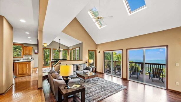 A spacious living area with a large window, a ceiling fan, and a view of the outdoors. - Wanderlust •HotTub •Spa Room w/Sauna •2 King Suites (Gatlinburg)