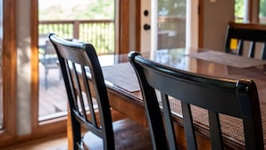 A dining area with a glass door leading to a deck, wooden chairs, and a table. - Wanderlust •HotTub •Spa Room w/Sauna •2 King Suites (Gatlinburg)