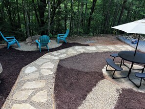 A patio area with a stone pathway, blue chairs, and a table with benches.