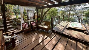 Une terrasse en bois avec des meubles en osier et un jacuzzi.