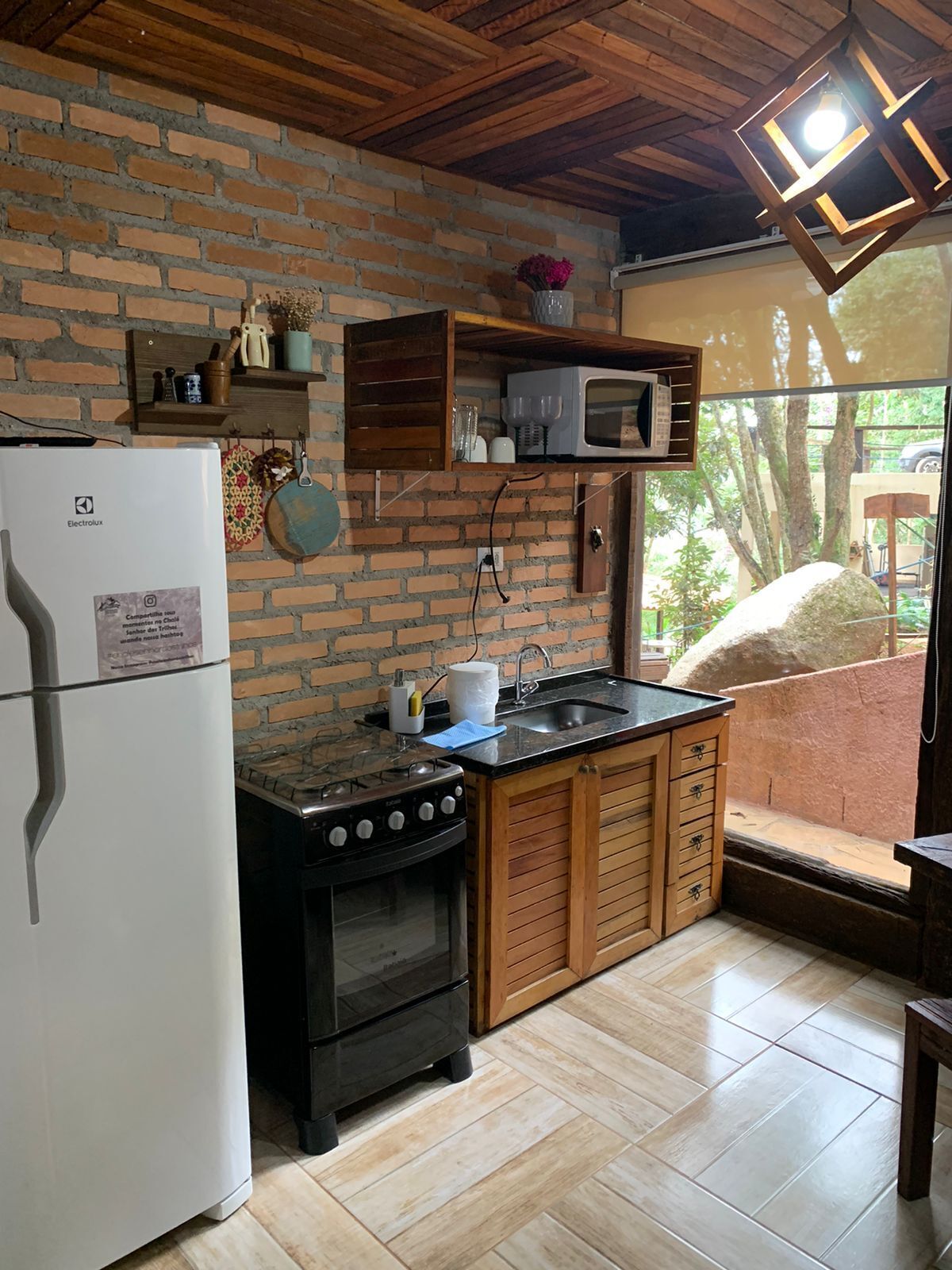 Una cocina compacta con refrigerador, estufa y armarios de madera.