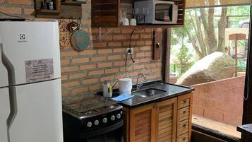 Una cocina compacta con refrigerador, estufa y armarios de madera.