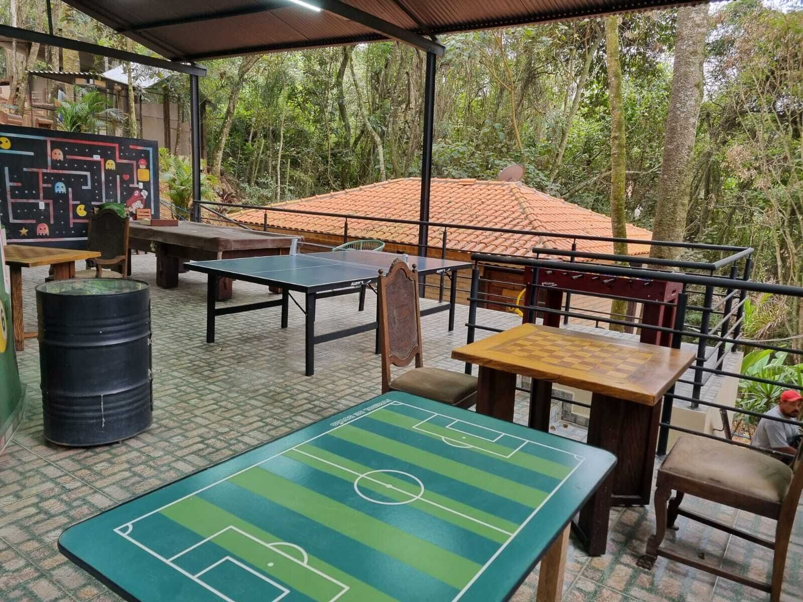 An outdoor area with a ping pong table, a chess table, and a table tennis table.
