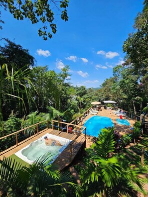 A pool area with a hot tub and lounge chairs surrounded by lush greenery. - Chales senhor dos trilhos (Mairipora)