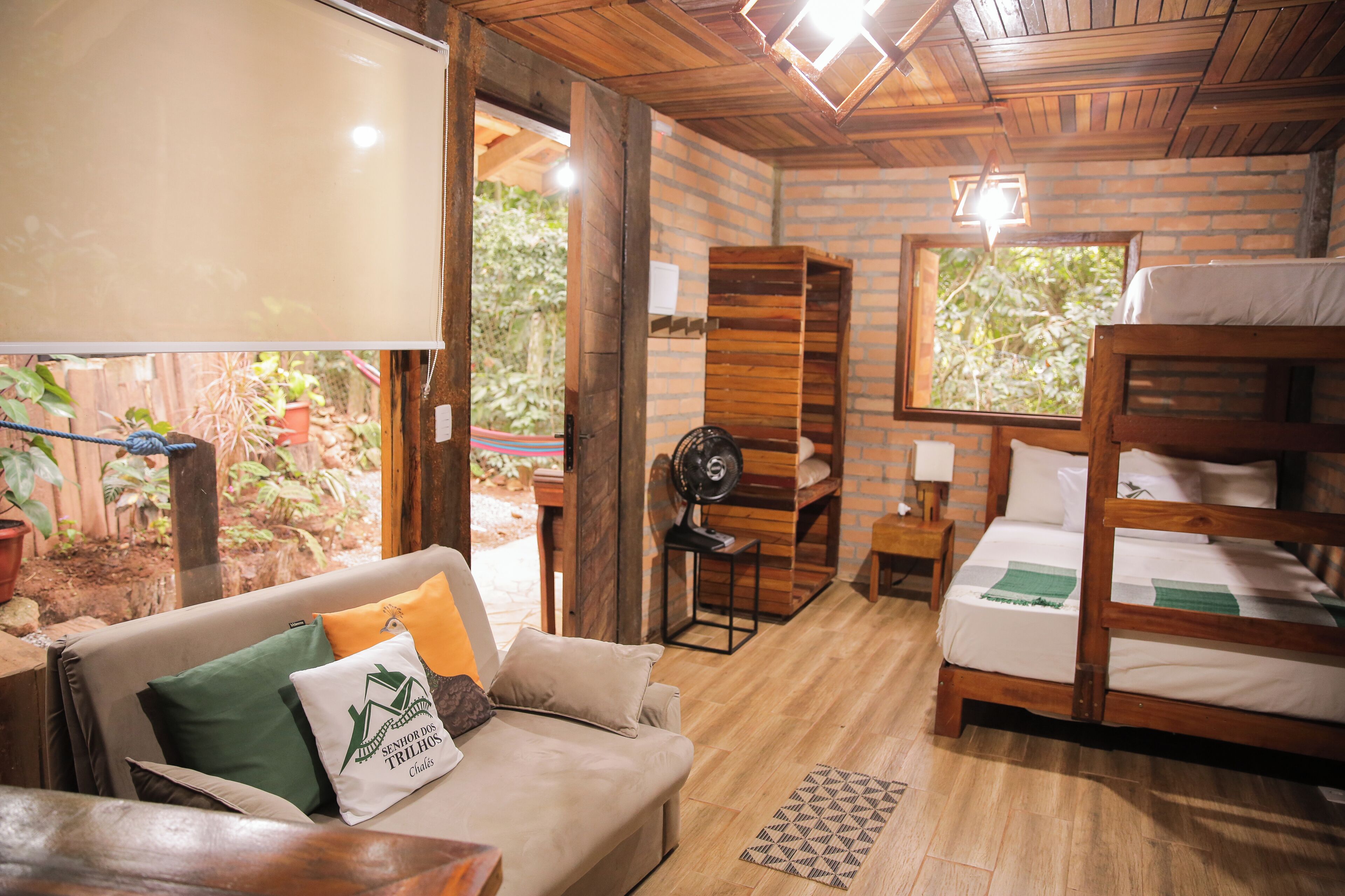 A cozy room with a wooden ceiling, a bed, a sofa, and a small table.