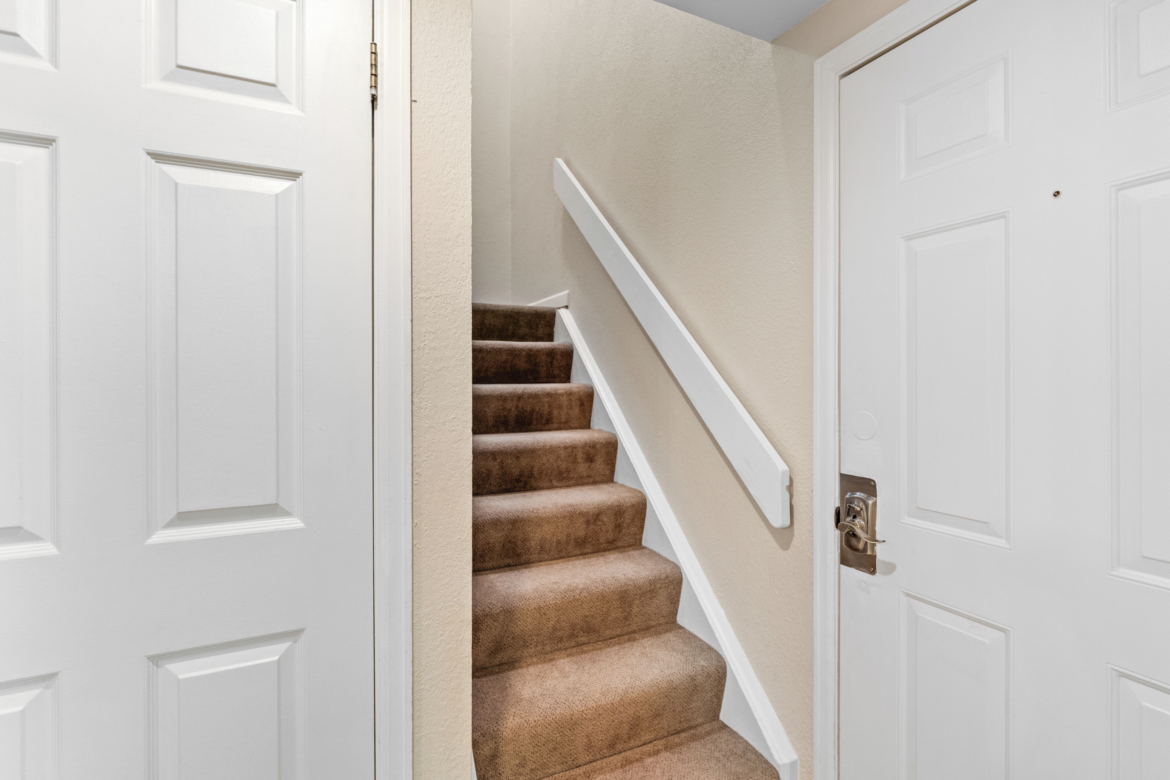 A staircase with carpeted steps and white walls.