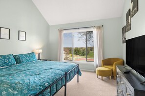 Ein Schlafzimmer mit Bett, Fernseher, Sessel und Fenster mit Aussicht.