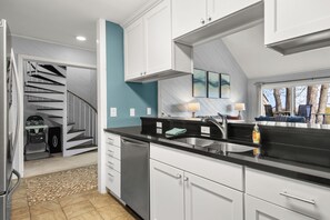 A modern kitchen with white cabinets, a black countertop, and a built-in dishwasher. - Venture Out at Shanty Creek Resort (Bellaire)