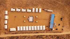 An aerial view of a campsite with multiple tents, a central building, and a blue-roofed structure.