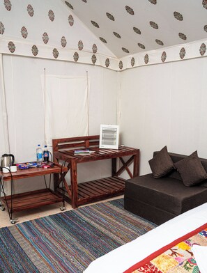 A room with a wooden desk, a small table, a sofa, and a patterned rug. - Shivam Resort - A Luxury Desert Camping (Jaisalmer)