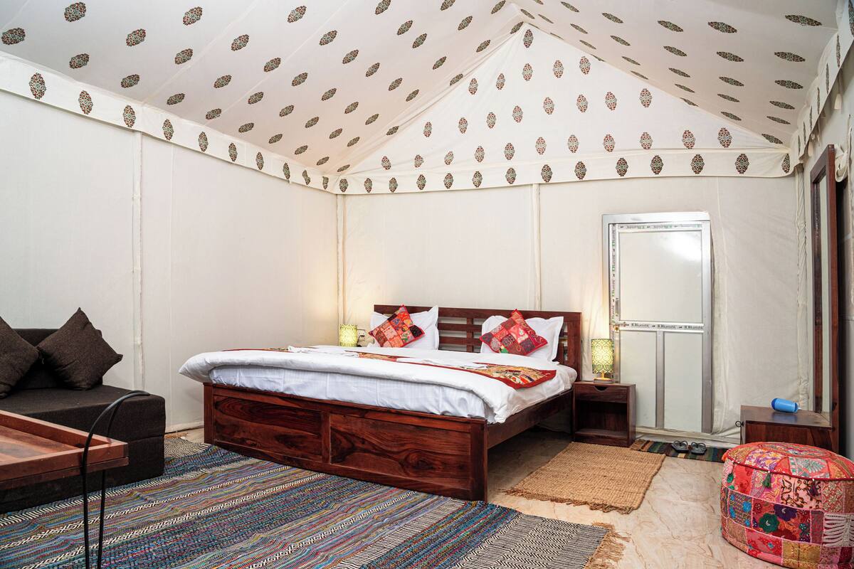 A bedroom with a wooden bed, a sofa, a patterned rug, and a decorative ceiling.